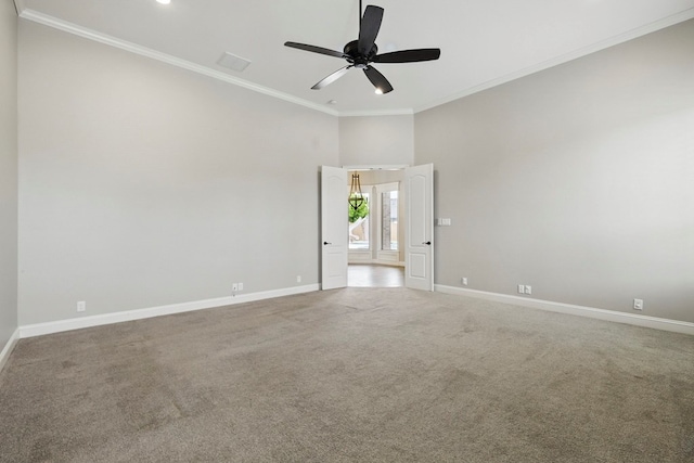 empty room with baseboards, a ceiling fan, carpet flooring, and ornamental molding