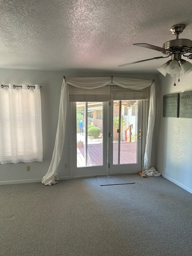 carpeted spare room with a textured ceiling and ceiling fan