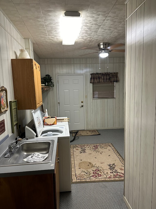 laundry room featuring ceiling fan, sink, carpet floors, and cabinets