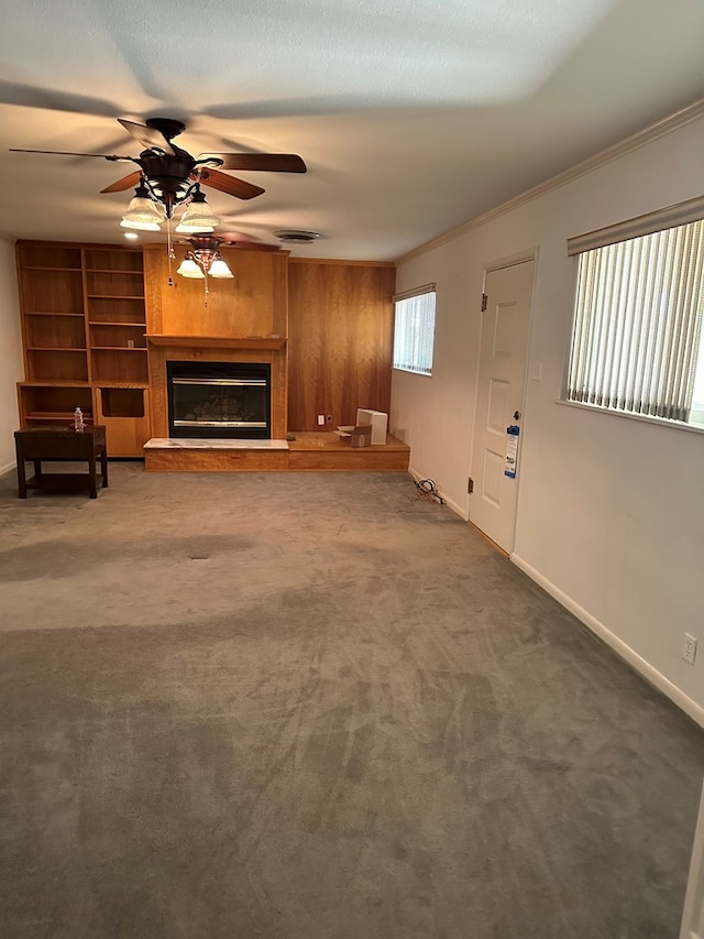 unfurnished living room featuring crown molding, ceiling fan, and dark carpet