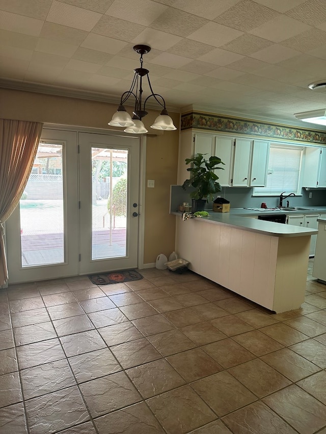 kitchen with white cabinetry, sink, a notable chandelier, kitchen peninsula, and pendant lighting