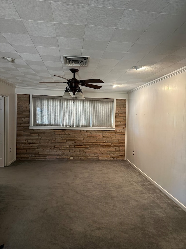 carpeted spare room featuring ceiling fan and wood walls