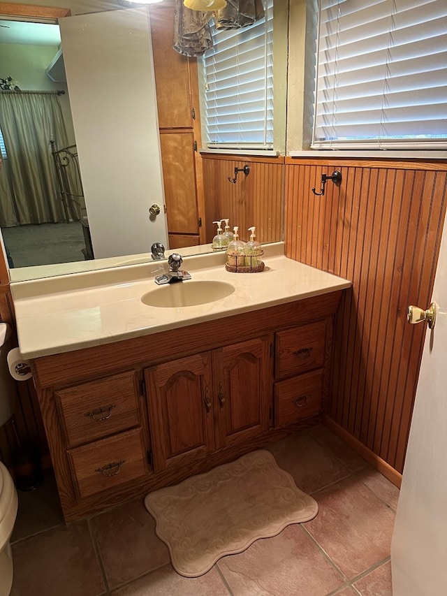 bathroom featuring wood walls, tile patterned flooring, vanity, and toilet