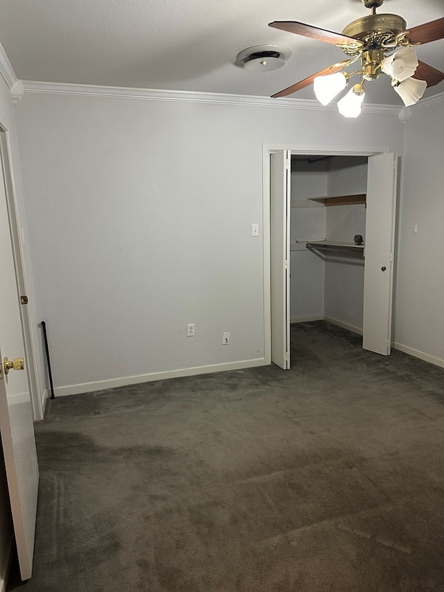 interior space with dark colored carpet, a closet, ceiling fan, and crown molding