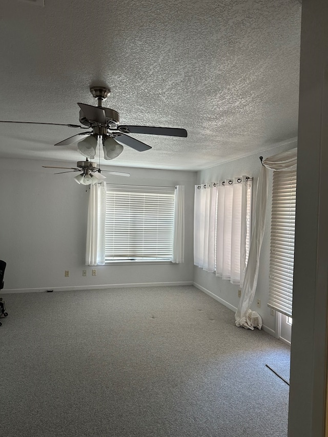 carpeted spare room featuring ceiling fan and a textured ceiling