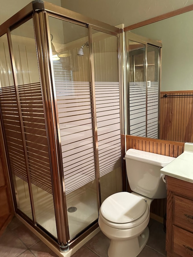 bathroom with tile patterned floors, vanity, a shower with door, and wooden walls