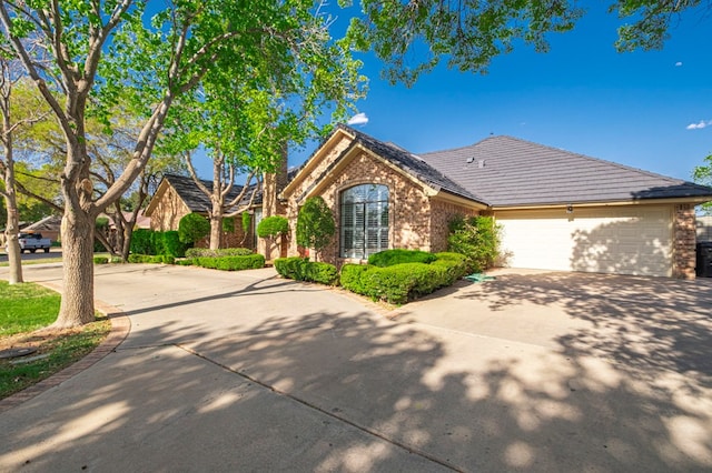 view of front of home featuring an attached garage, driveway, and brick siding