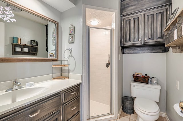 bathroom with a shower stall, vanity, tile patterned flooring, toilet, and baseboards