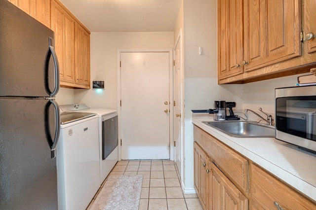clothes washing area with a sink, light tile patterned floors, separate washer and dryer, and laundry area