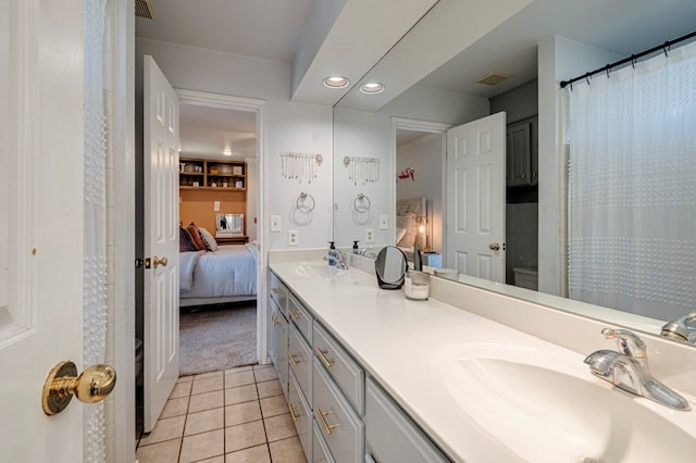 ensuite bathroom with a sink, ensuite bathroom, double vanity, and tile patterned flooring