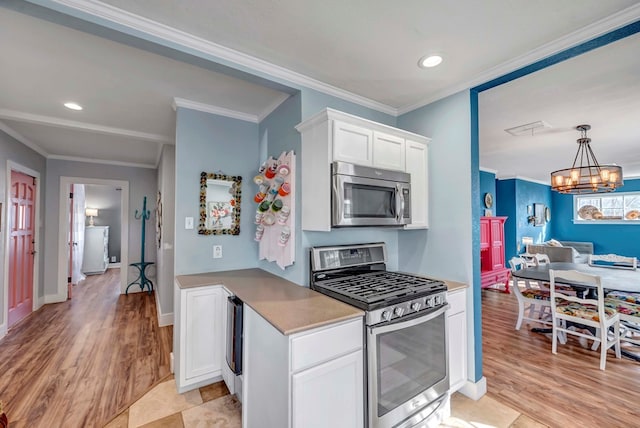 611 Storey Ave, Midland, TX 79703 - kitchen featuring appliances with stainless steel finishes, white cabinetry, light wood finished floors, a chandelier, and ornamental molding