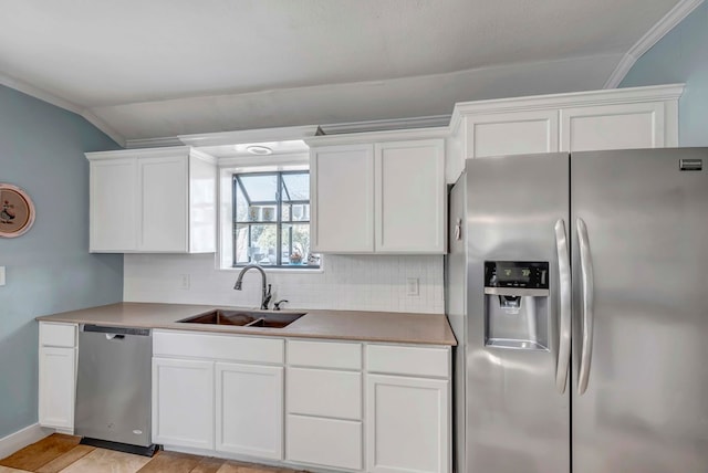 611 Storey Ave, Midland, TX 79703 - kitchen featuring stainless steel appliances, a sink, vaulted ceiling, decorative backsplash, and white cabinets