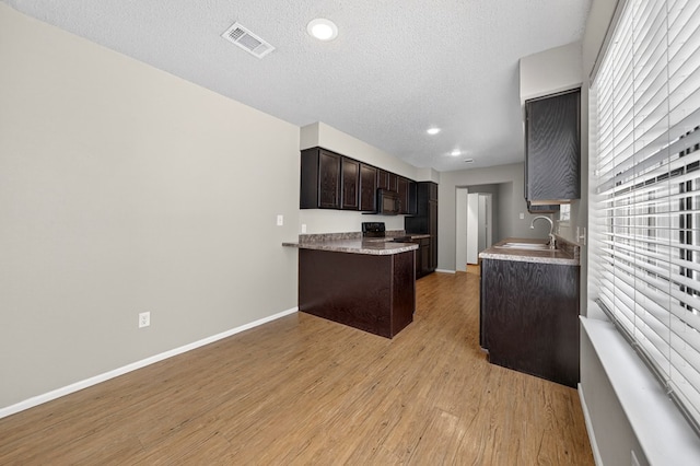3237 Preston Dr, Midland, TX 79707 - kitchen featuring dark brown cabinetry, light wood-type flooring, black microwave, a textured ceiling, and recessed lighting