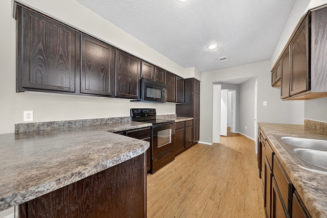 3237 Preston Dr, Midland, TX 79707 - kitchen with black appliances, dark brown cabinetry, light wood-type flooring, and a textured ceiling