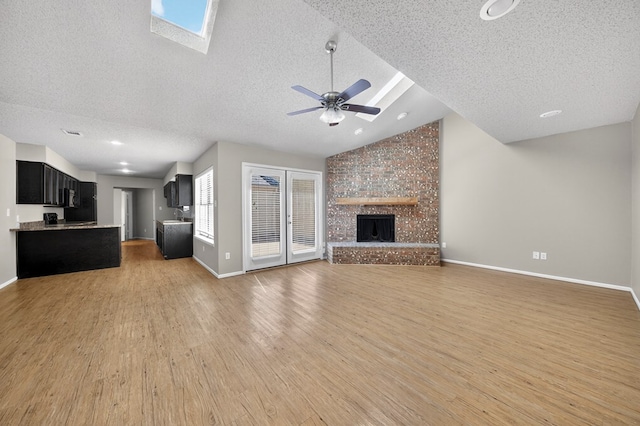 3237 Preston Dr, Midland, TX 79707 - unfurnished living room featuring a textured ceiling, light wood-style flooring, vaulted ceiling, a ceiling fan, and a brick fireplace