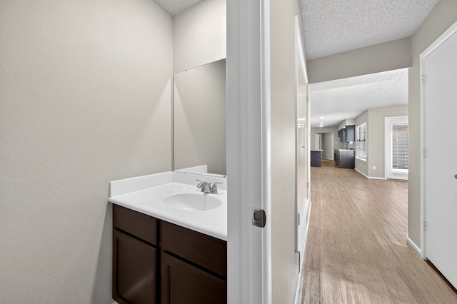3237 Preston Dr, Midland, TX 79707 - bathroom with a textured ceiling, vanity, and wood finished floors