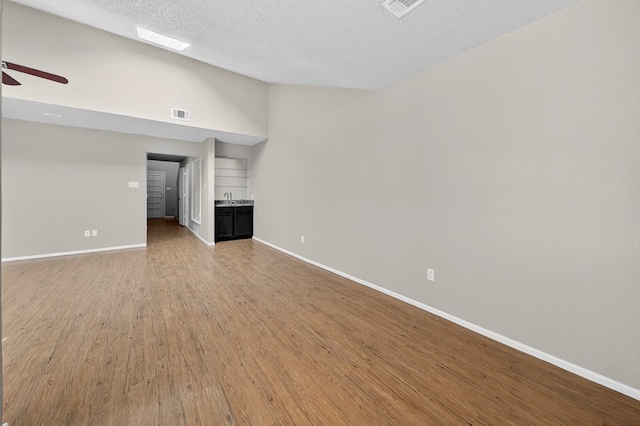 3237 Preston Dr, Midland, TX 79707 - unfurnished living room with light wood finished floors, a textured ceiling, ceiling fan, and high vaulted ceiling