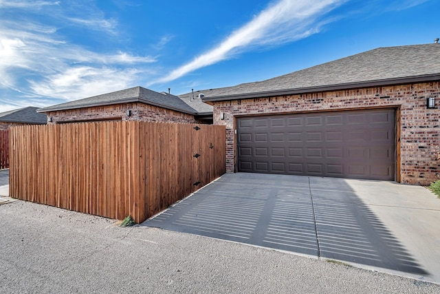 garage featuring concrete driveway and fence