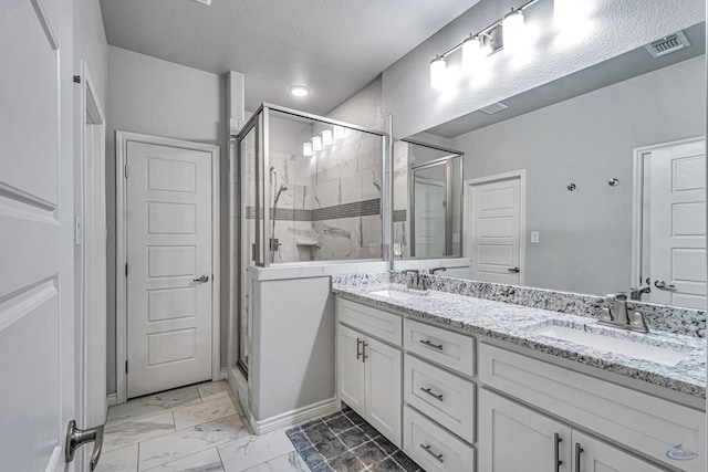 bathroom featuring double vanity, visible vents, a shower stall, and a sink