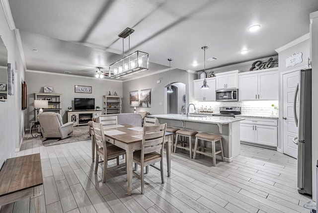 dining space with arched walkways, wood tiled floor, a glass covered fireplace, and crown molding