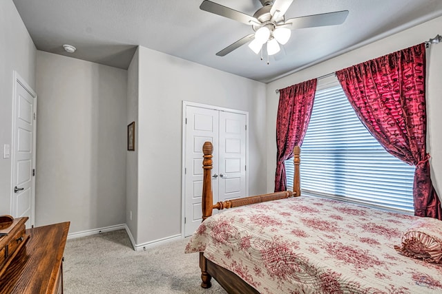 carpeted bedroom with a closet, baseboards, and a ceiling fan