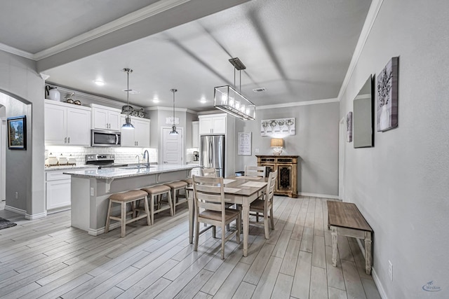 dining space with baseboards, light wood finished floors, and ornamental molding