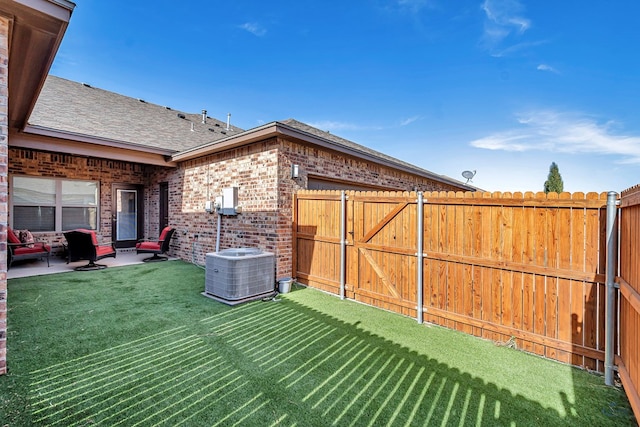 view of yard with a patio area, central air condition unit, a gate, and fence