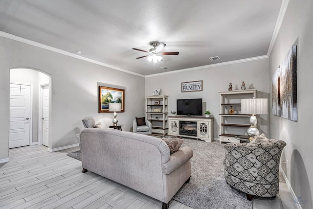 living room featuring a ceiling fan, baseboards, wood finished floors, arched walkways, and ornamental molding