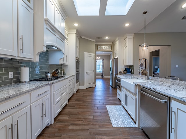 kitchen featuring white cabinetry, stainless steel appliances, backsplash, and a sink