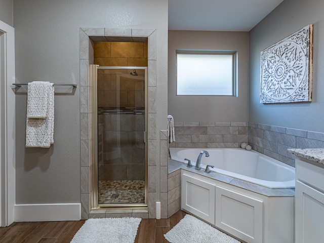 bathroom with a bath, a shower stall, wood finished floors, and vanity