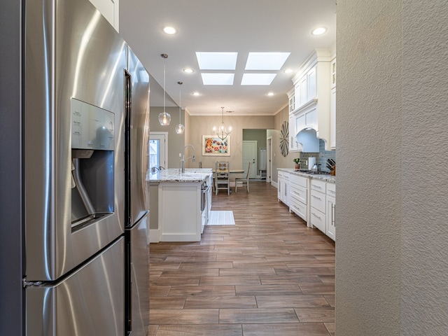 kitchen featuring dark wood-style floors, a chandelier, stainless steel appliances, white cabinetry, and a skylight