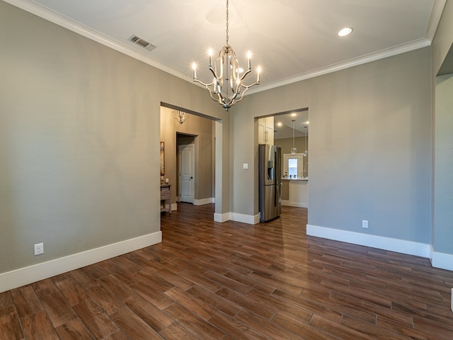 spare room featuring dark wood-type flooring, a chandelier, crown molding, and visible vents