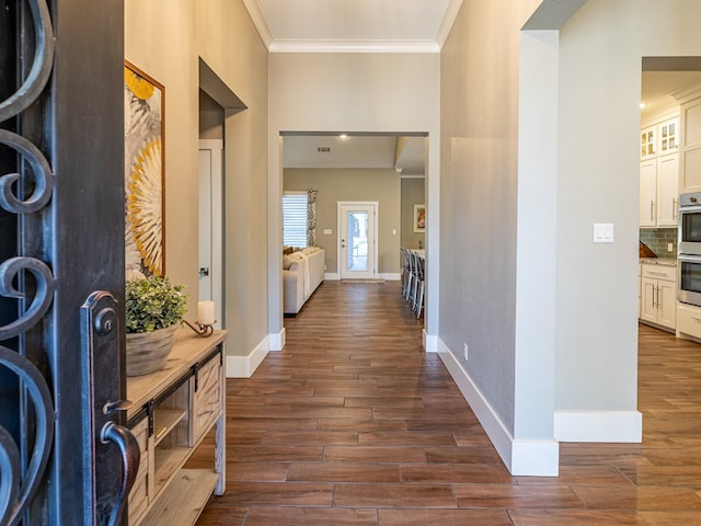 foyer featuring dark wood-style flooring, crown molding, and baseboards