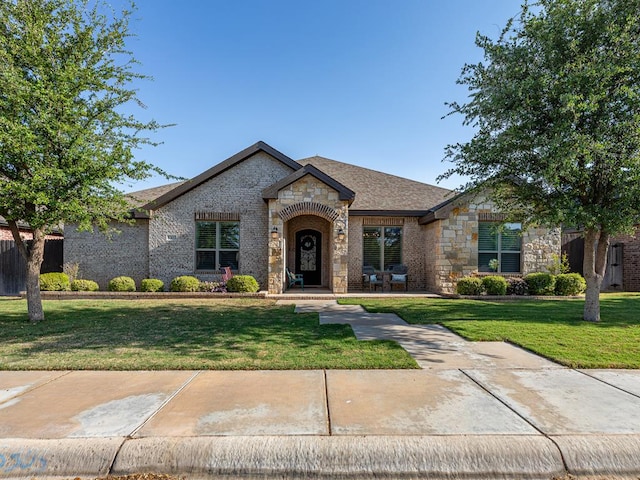 view of front of home featuring a front yard, brick siding, and stone siding