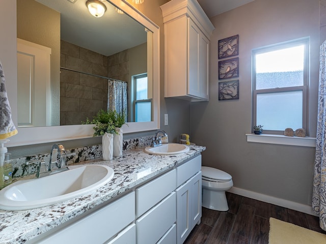 bathroom featuring baseboards, wood finished floors, toilet, and a sink