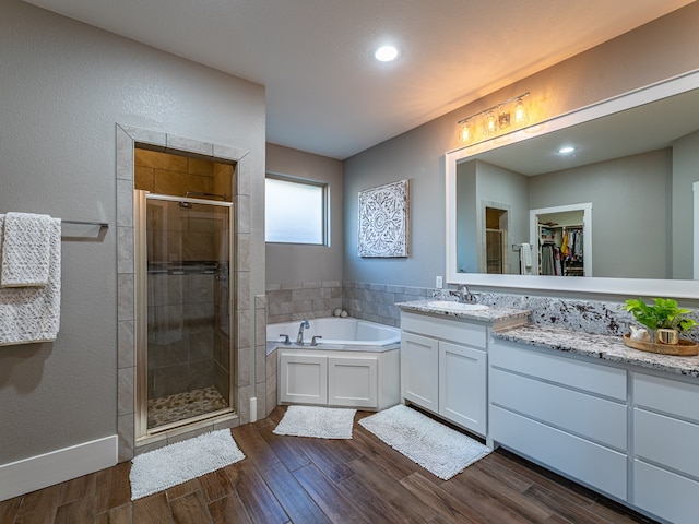 full bath featuring wood finished floors, a shower stall, a garden tub, and vanity