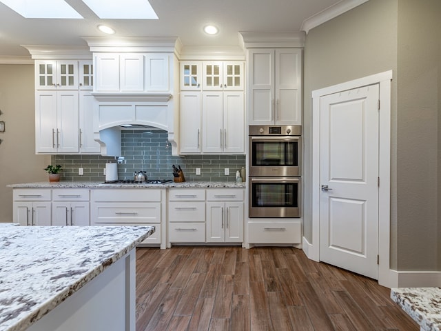kitchen featuring dark wood finished floors, a skylight, ornamental molding, and appliances with stainless steel finishes