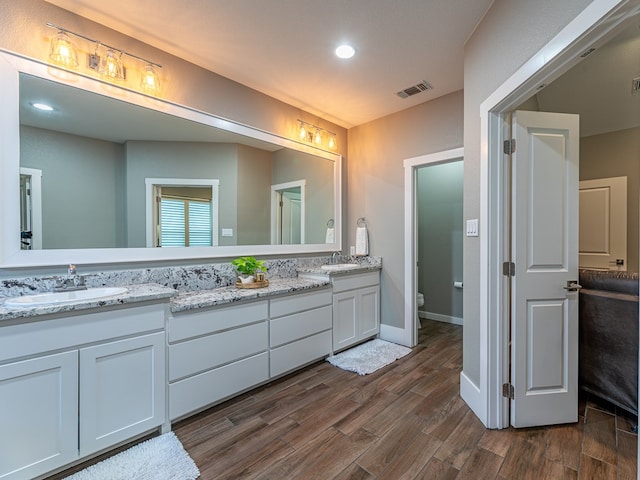 full bathroom with visible vents, wood finished floors, double vanity, and a sink