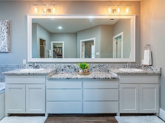 full bathroom with wood tiled floor, double vanity, a sink, and a stall shower