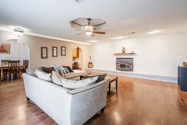 living room featuring ceiling fan, dark hardwood / wood-style floors, a textured ceiling, and brick wall