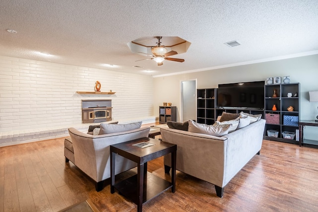 living room featuring hardwood / wood-style flooring, ornamental molding, and a textured ceiling