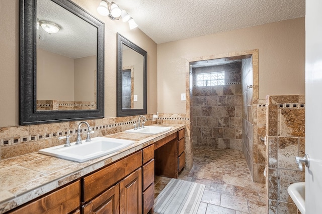 bathroom with vanity, tiled shower, and a textured ceiling