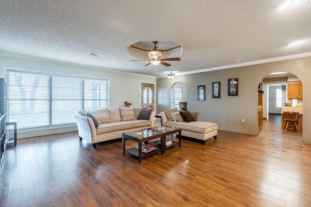 living room with ornamental molding, hardwood / wood-style floors, ceiling fan, and a textured ceiling