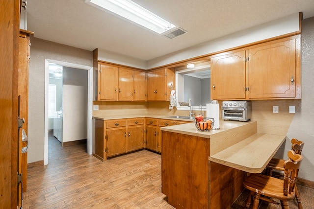 kitchen featuring sink, kitchen peninsula, light hardwood / wood-style floors, and a breakfast bar area