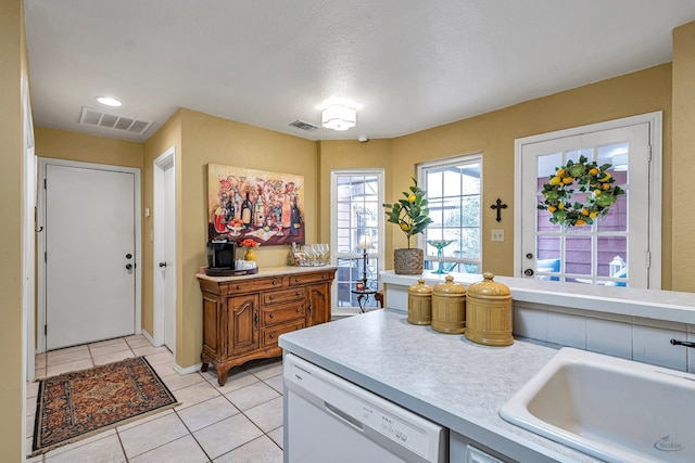 kitchen with sink, a textured ceiling, dishwasher, and light tile patterned flooring