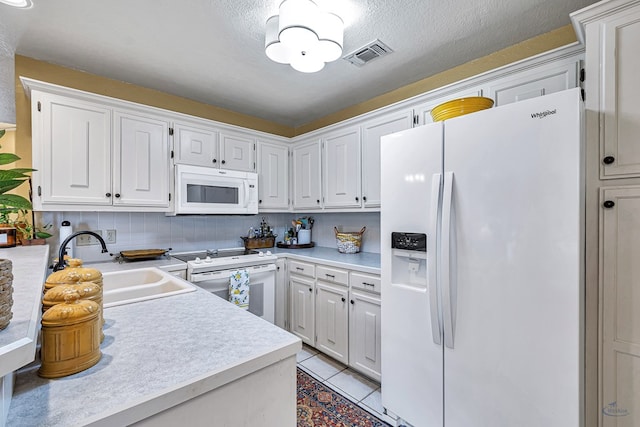 kitchen featuring white appliances, white cabinets, a textured ceiling, sink, and light tile patterned floors