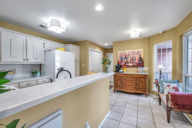 kitchen featuring backsplash, white cabinetry, a textured ceiling, light tile patterned floors, and white fridge with ice dispenser