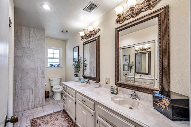 bathroom with a textured ceiling, toilet, tile patterned flooring, and vanity