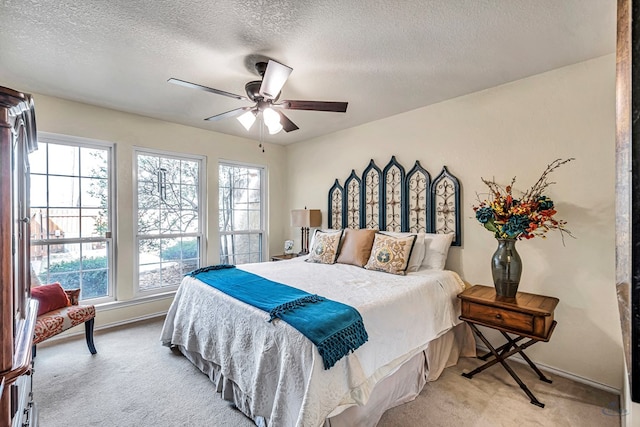 carpeted bedroom featuring ceiling fan and a textured ceiling