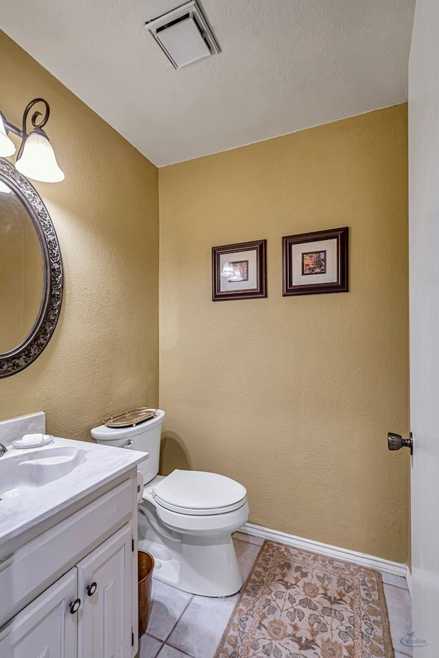 bathroom featuring toilet, vanity, tile patterned floors, and a textured ceiling